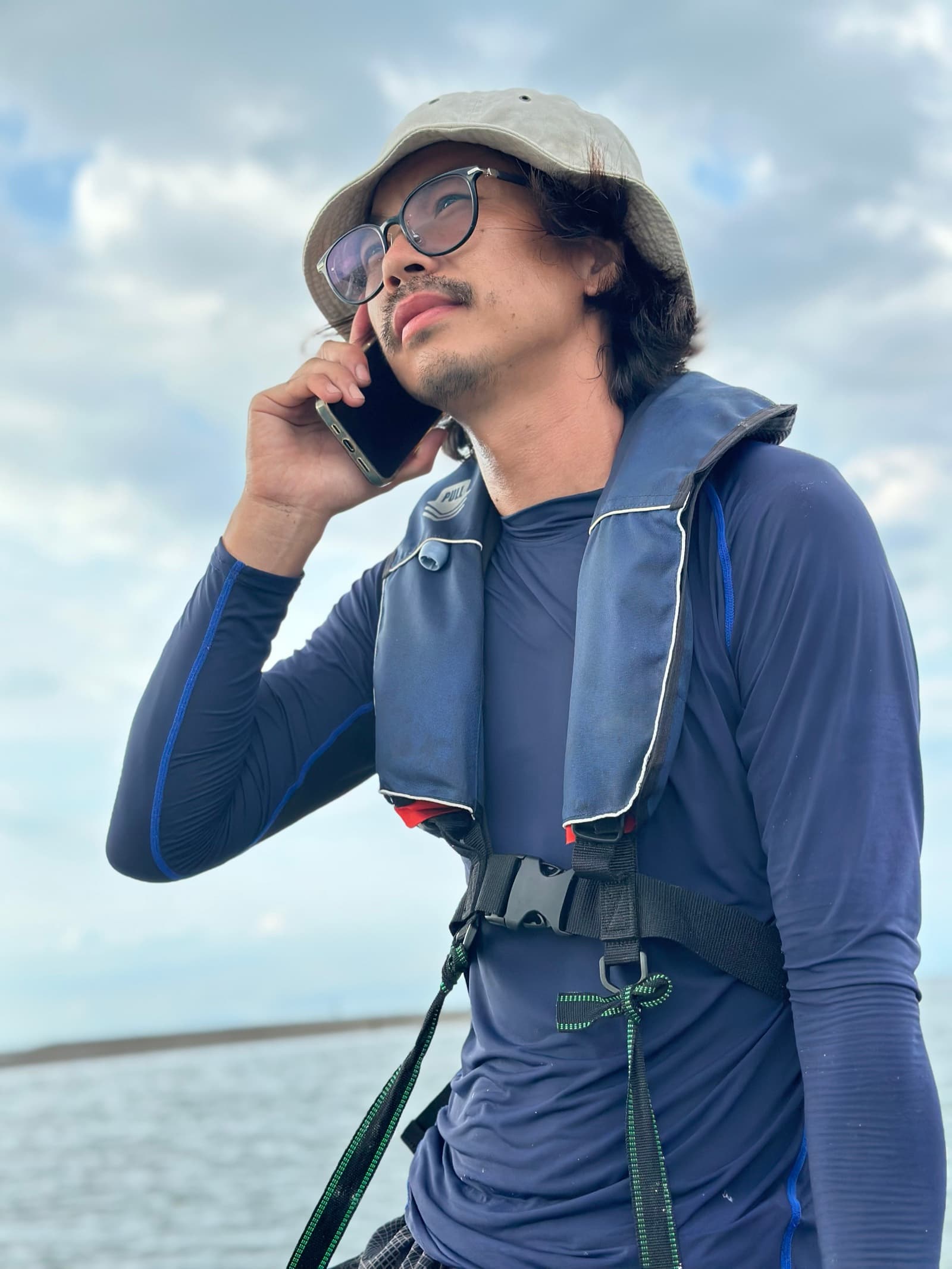 ライフジャケットを着て、海の上で電話をしながら現場に立つ人物